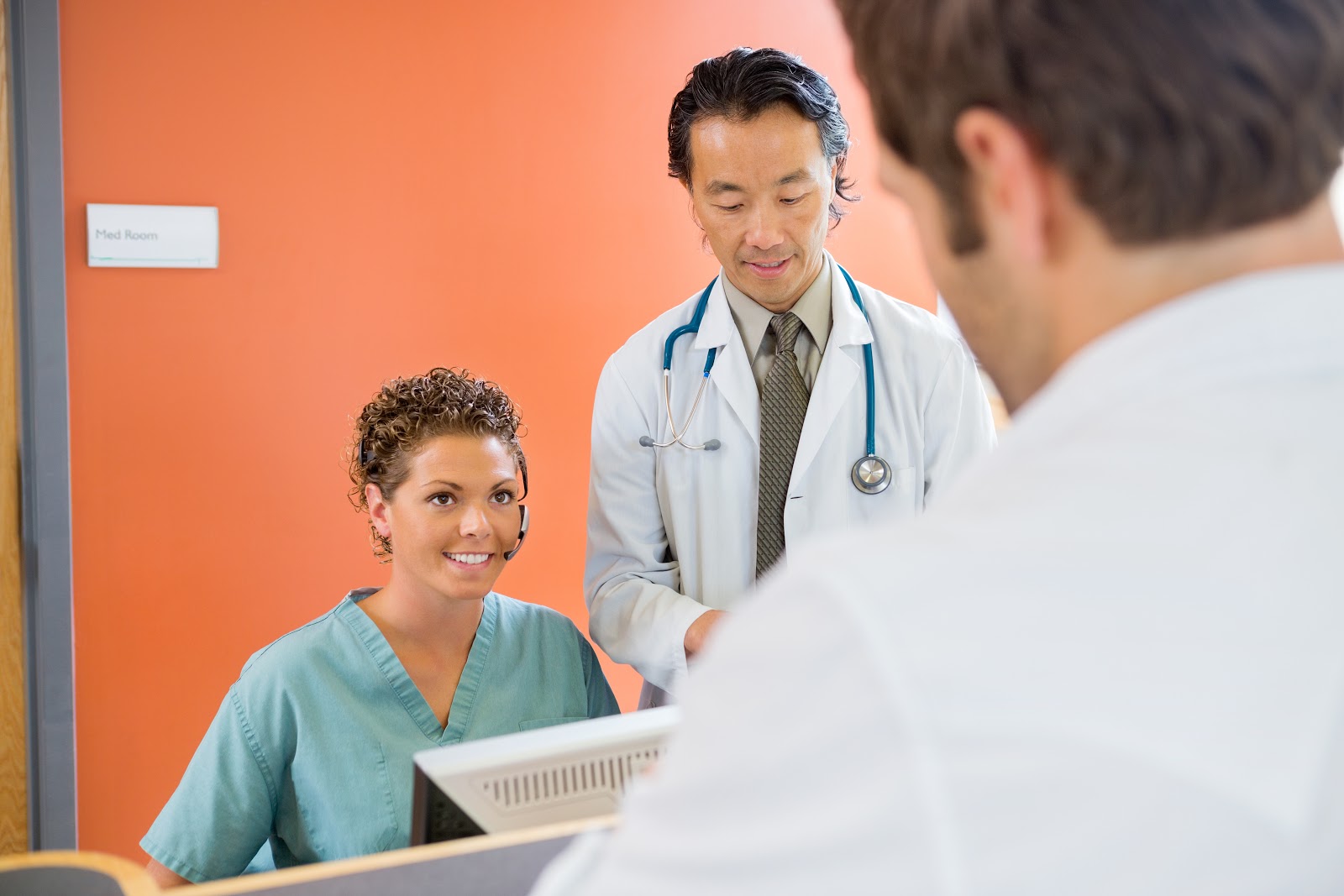 two doctors and a receptionist having a conversation in a clinic