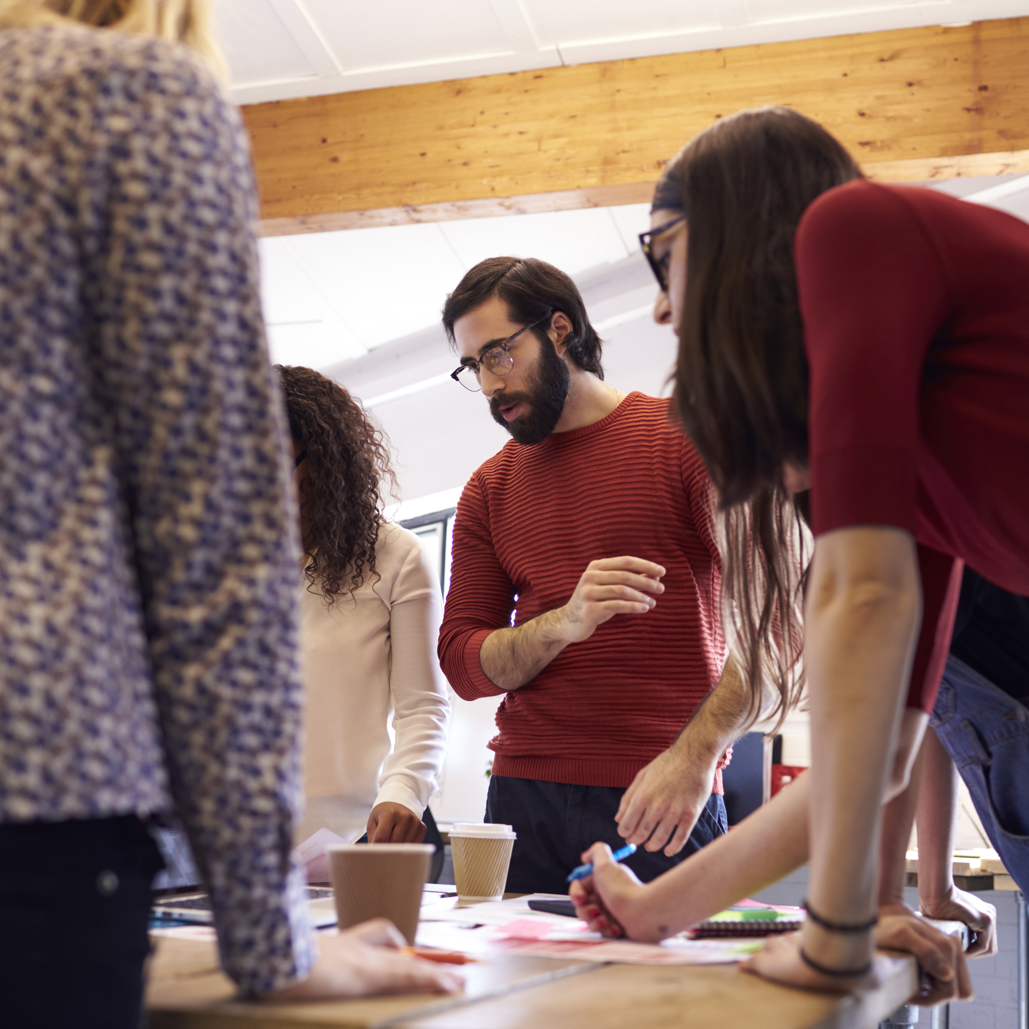 a group of co-workers having a discussion about a holiday event with planning materials spread out in front of them