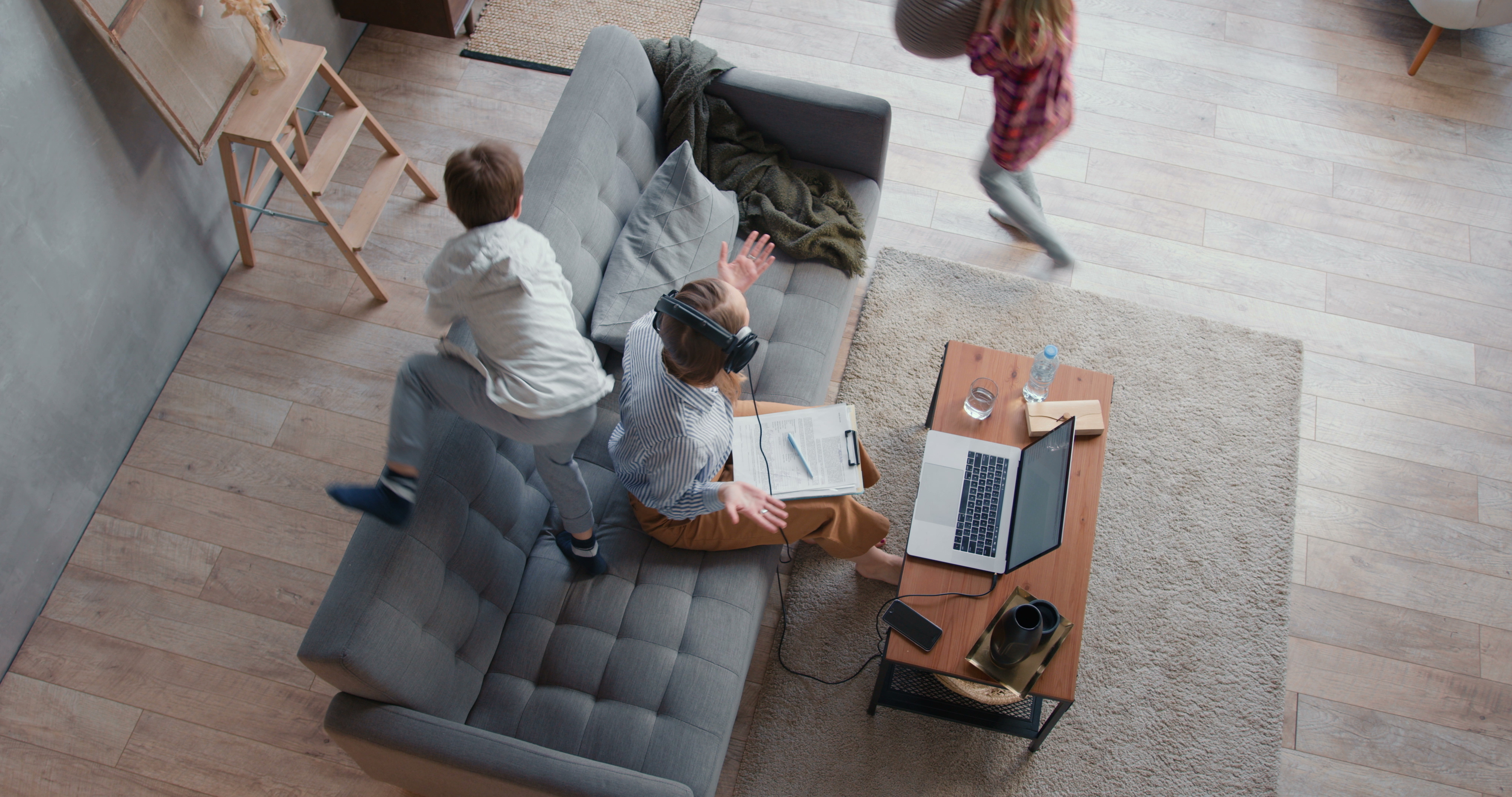 a father working in the living room of his home on a laptop computer with his children playing <b>Productivity at Home</b><br />