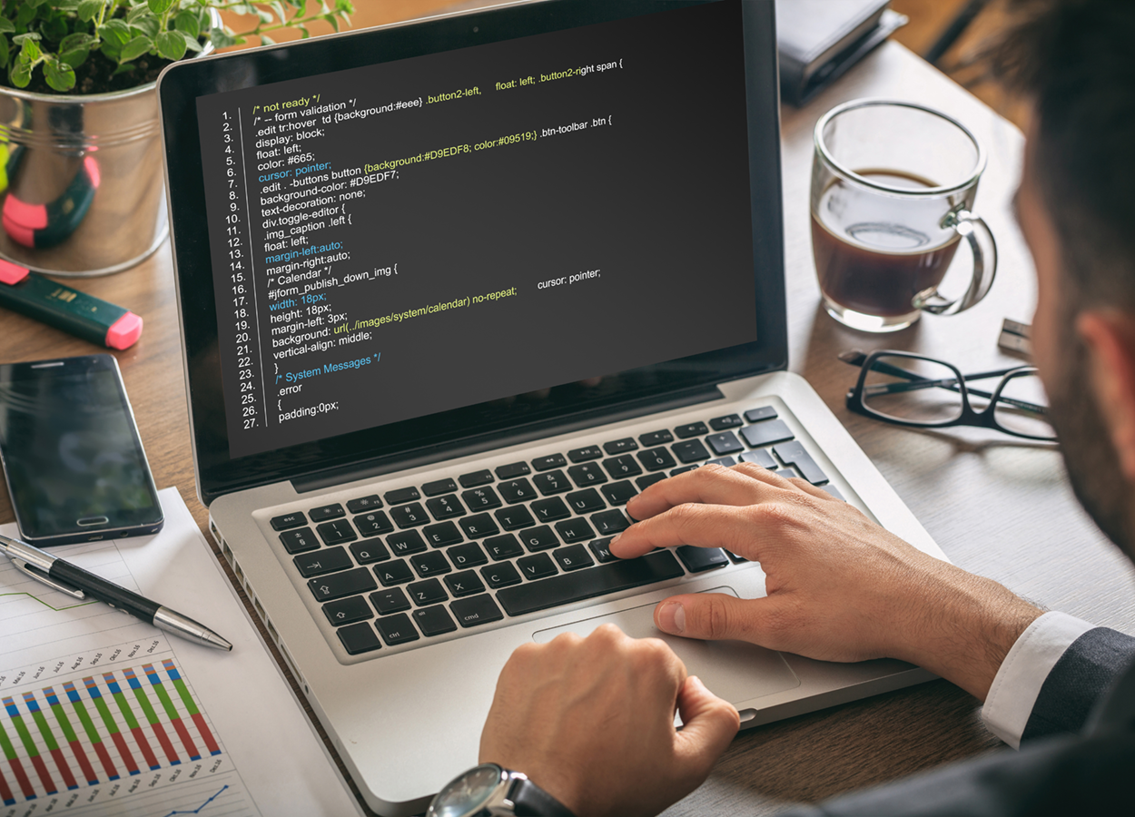 A programmer writing code on their laptop.