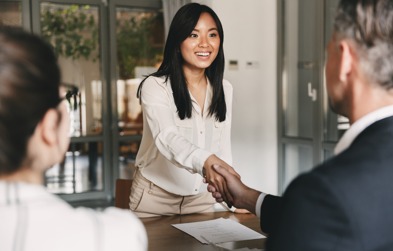 a young woman shaking hands with two professionally-dressed people