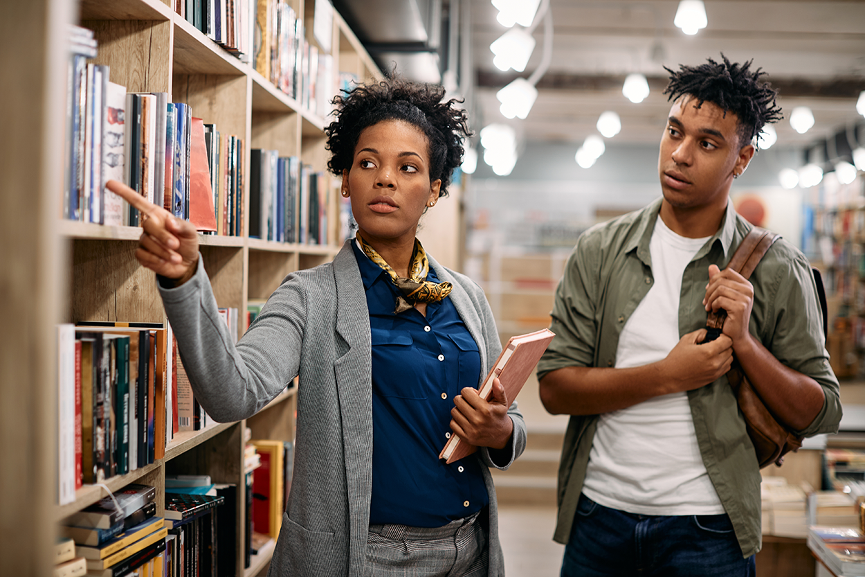 A librarian helps a student find materials in a library.