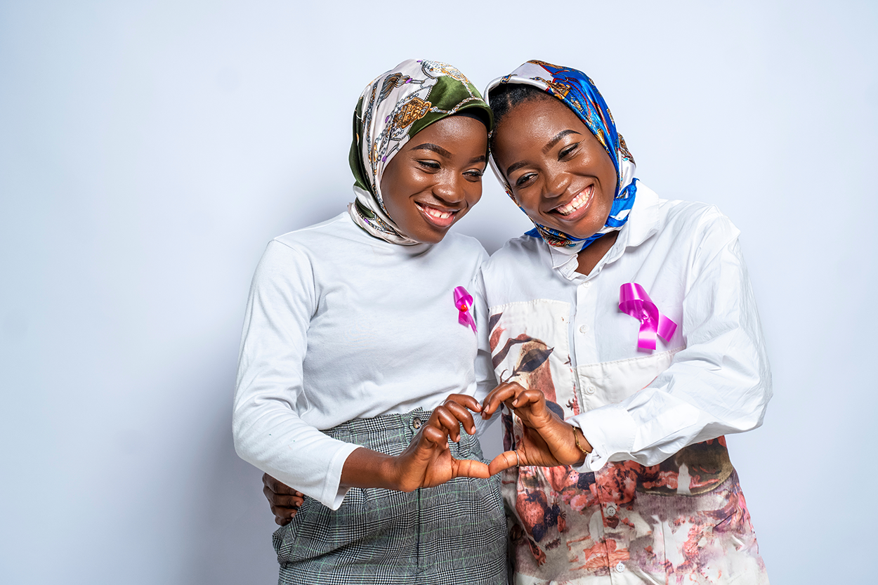 A photo of identical twins putting hearts up with their hands.