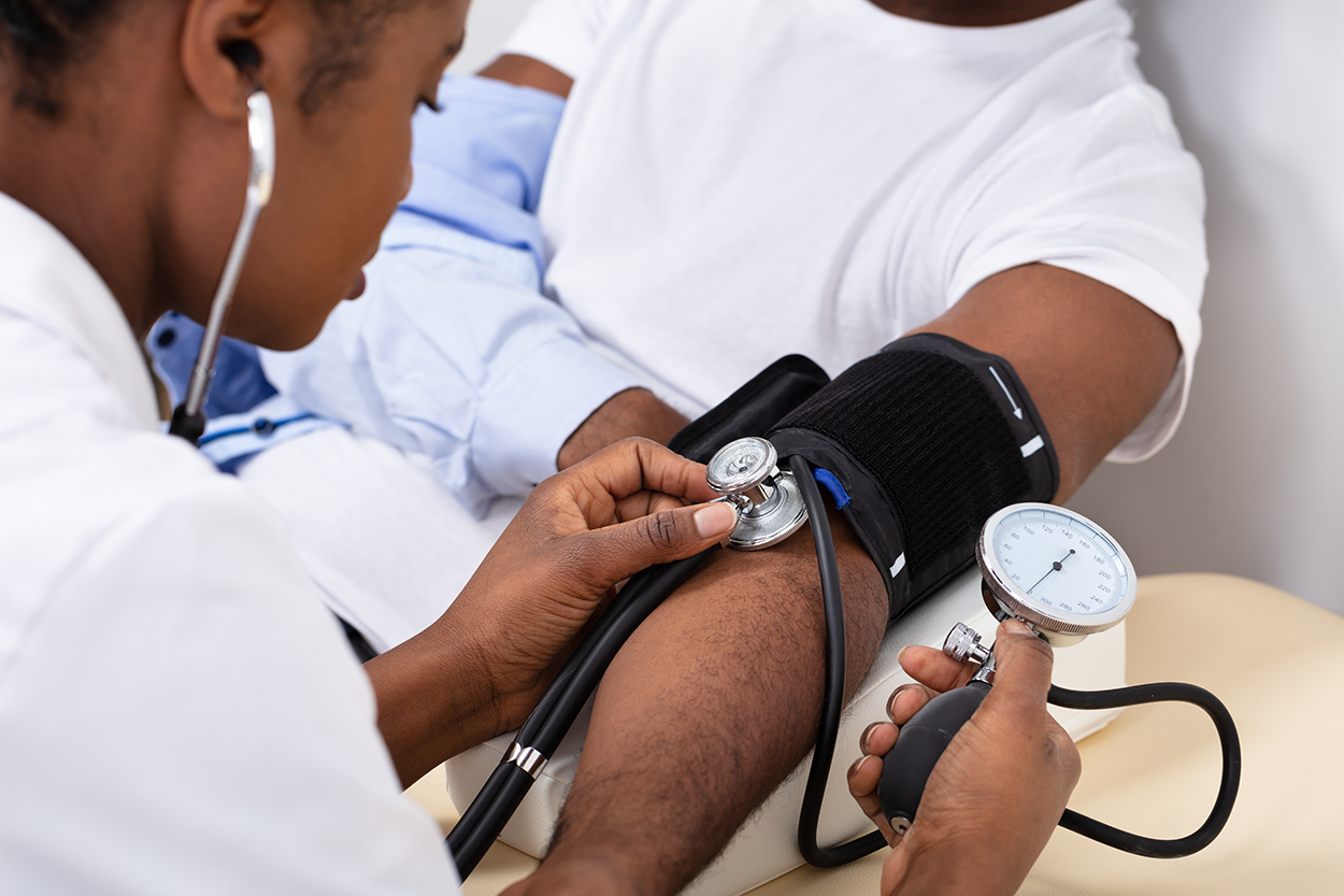 A doctor uses a sphygmomanometer to measure the blood pressure of a seated patient.