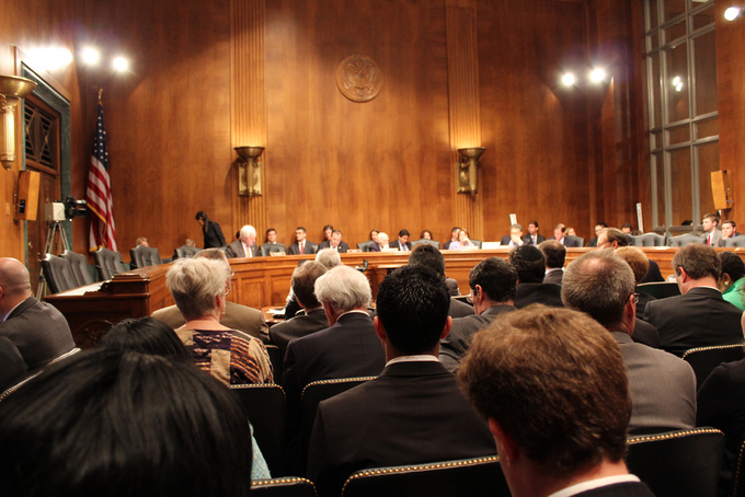 A courtroom is shown with a panel of people speaking in front of an audience.