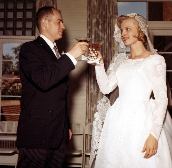 The toasts that are given at a wedding are an example of special occasion speeches. A man in a suit and a woman in a wedding dress each hold a glass and smile at one another while toasting.