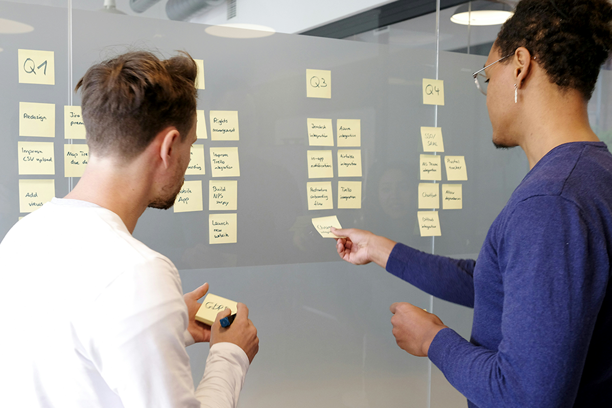 two office workers arranging post it notes in columbs