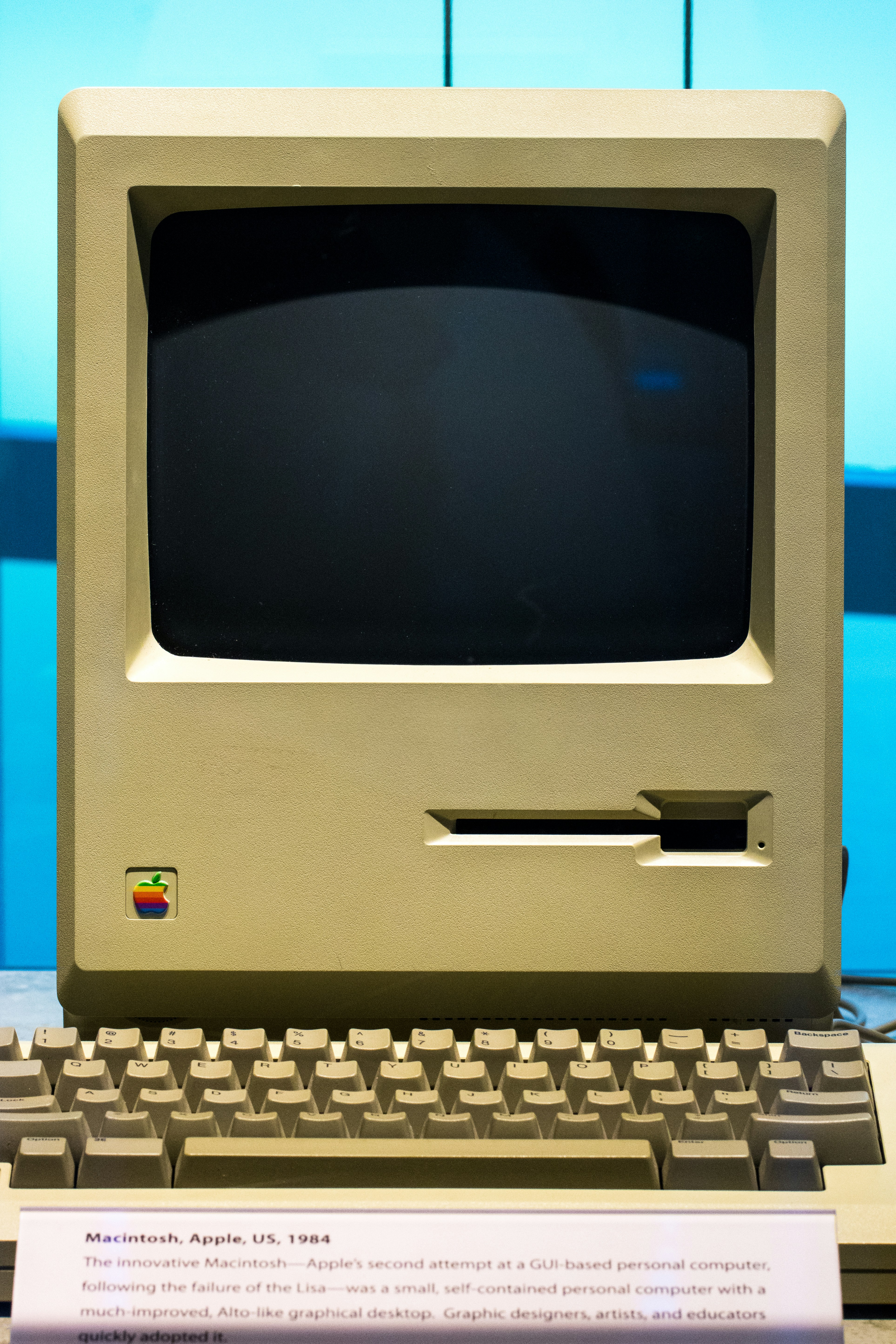 a vintage Apple Macintosh computer from 1984 showing a monitor, floppy disk drive, and keyboard