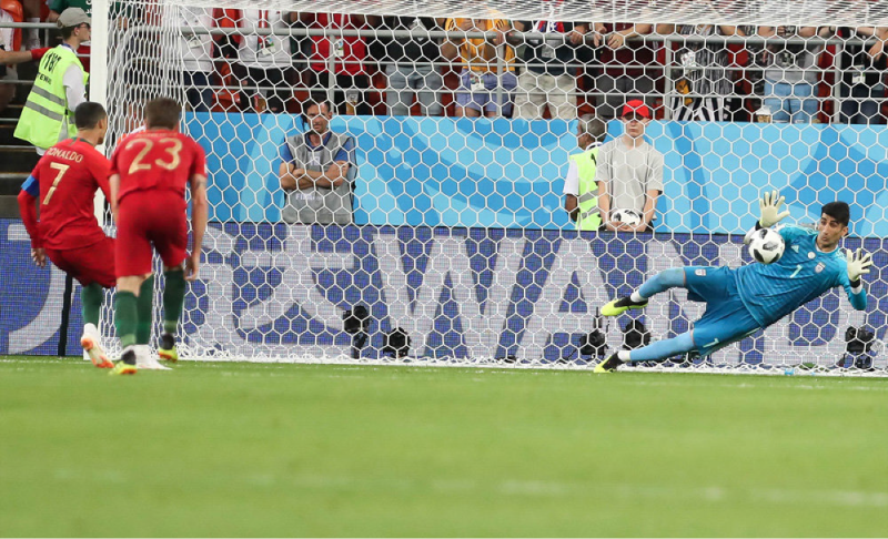 A keeper in front of their net as they fall towards a soccer ball kicked towards them.