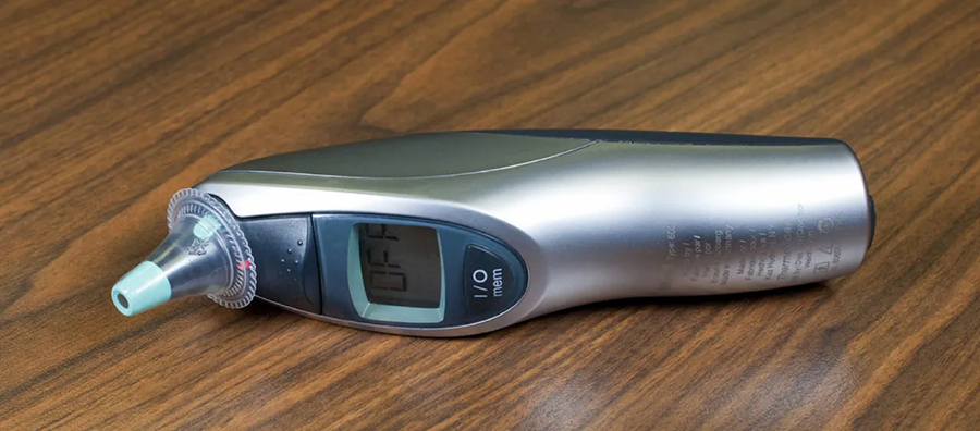 A photo shows a silver tympanic thermometer with a narrow tip to insert into an ear.