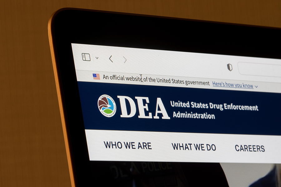 A laptop screen displaying the official website of the United States Drug Enforcement Administration (DEA), with navigation links for 'Who We Are,' 'What We Do,' and 'Careers.